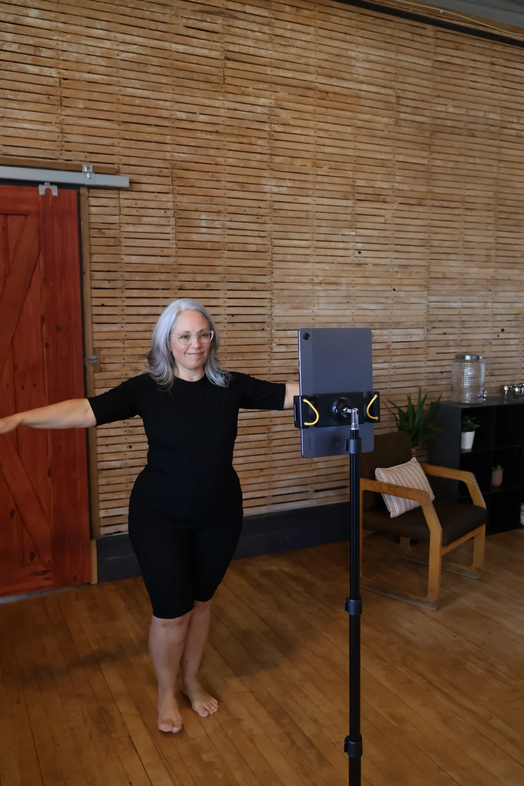 A client standing with her arms extended in front of the Fit3D scanning tablet